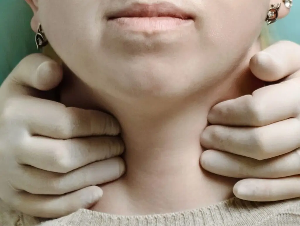 Збільшення щитоподібної залози може тиснути на трахею та викликати відчуття кому в горлі.
